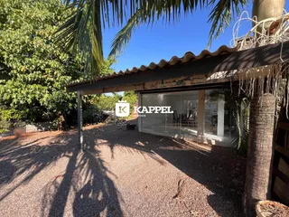 Foto da fachada de uma casa com um pátio coberto e vegetação exuberante.
