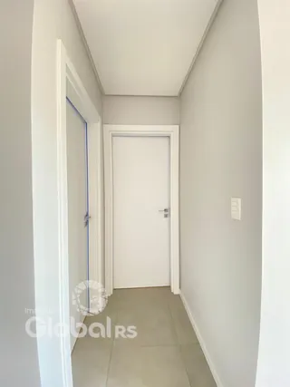 Hall de entrada com paredes brancas e porta branca.