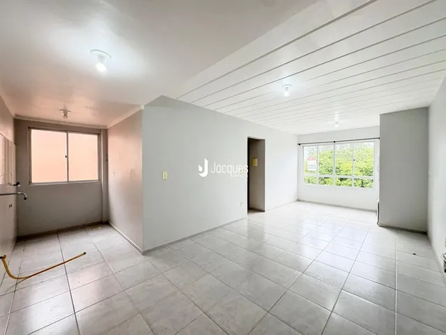 Interior de uma sala ampla com piso de cerâmica e janelas grandes.