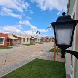 Vista externa de uma propriedade com gramado e área pavimentada sob céu azul.