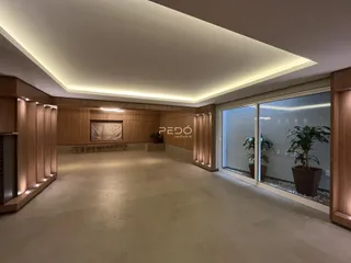 Ambiente interno de uma sala ampla com revestimento de madeira e iluminação embutida.