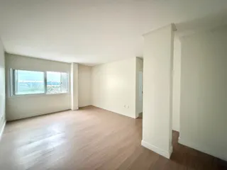 Sala de estar ampla com grande janela que oferece uma vista da paisagem externa.