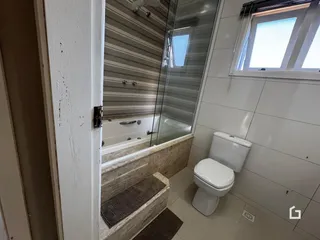 Foto de um banheiro com box de vidro e revestimento cerâmico.