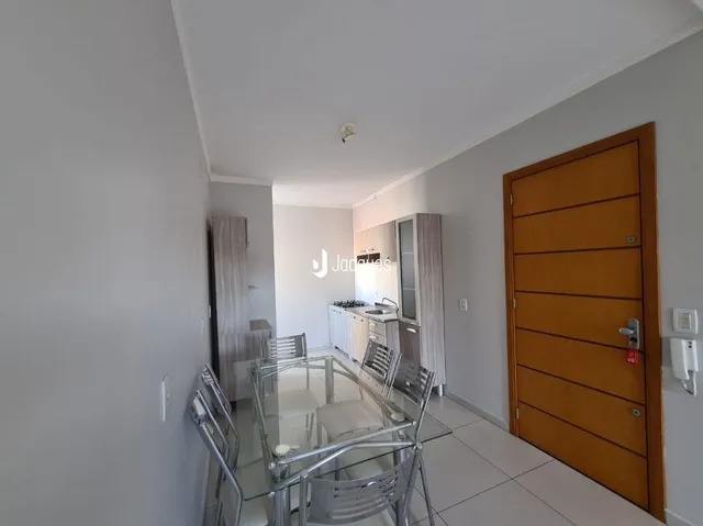 Hall de entrada com porta de madeira e mesa de vidro em um imóvel.