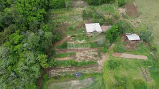 Vista aérea de um terreno rural com vegetação e algumas estruturas.