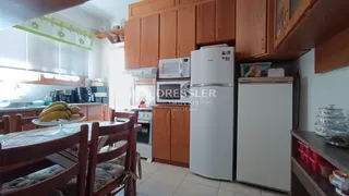 Ambiente de cozinha e jantar com armários de madeira e eletrodomésticos brancos.
