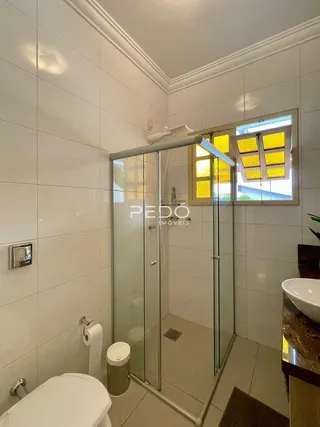 Foto de um banheiro com revestimento branco e box de vidro.