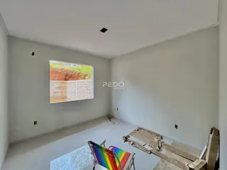Interior de um cômodo com paredes brancas e piso em obra.