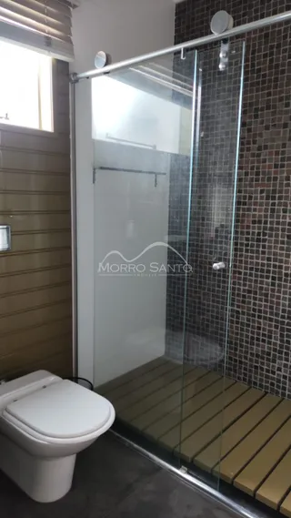Foto de um banheiro com box de vidro e revestimento de tijolos aparentes.