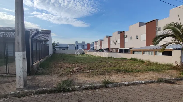 Vista externa de um terreno com construções residenciais ao fundo.