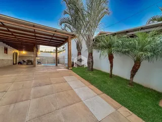 Área externa com piso de cerâmica e gramado ao lado de palmeiras.
