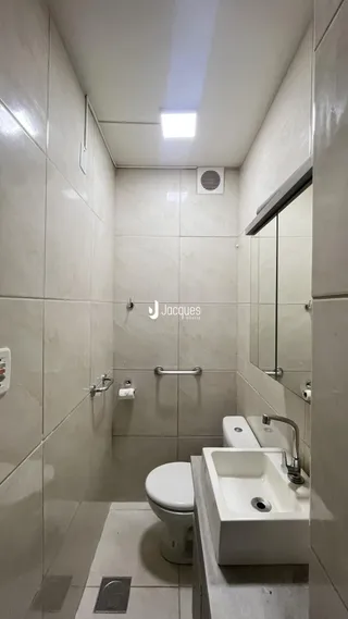 Foto de um banheiro com revestimento cerâmico e louças brancas.