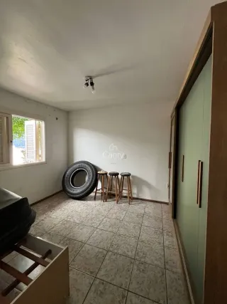 Uma foto interna mostra uma sala com piso de cerâmica e um sofá no primeiro plano.