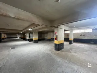 Vista do corredor interno de um imóvel com estrutura de concreto aparente.