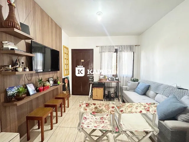 Sala de estar com sofá, televisão e móveis de madeira em um apartamento.