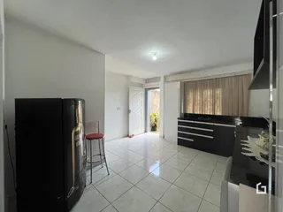 Ambiente interno de uma sala de estar com piso de cerâmica clara e móveis de cozinha.