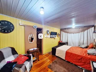 Quarto com cama e sofá em ambiente interno com piso de madeira.