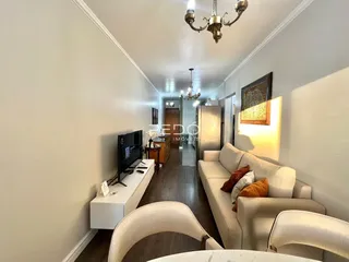 Hall de uma sala de estar com sofá e televisão em um apartamento.