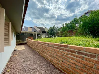 Vista externa de uma propriedade com muro de tijolos e jardim.