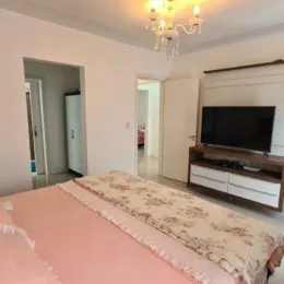 Foto de uma cama com roupa de cama rosa em um quarto.