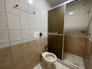 Banheiro com revestimento cerâmico e box de vidro.