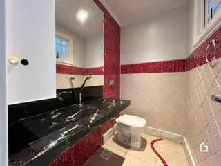 Foto de um banheiro com revestimento de azulejos vermelhos e brancos.