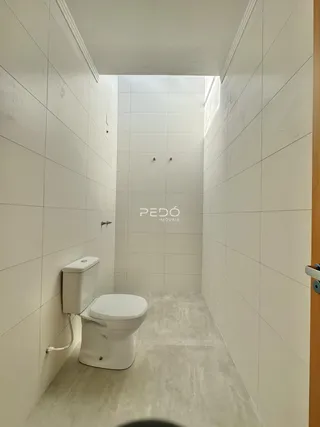 Corredor de banheiro com paredes brancas e azulejos.