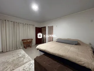Quarto com cama grande e cortinas brancas.