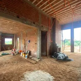 Foto de um espaço interno em construção com paredes de tijolo aparente e teto de madeira.