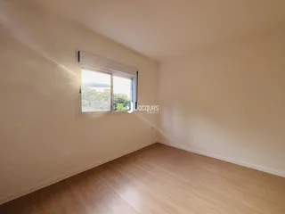 Vista interna de um cômodo com piso de madeira e janela para a paisagem.