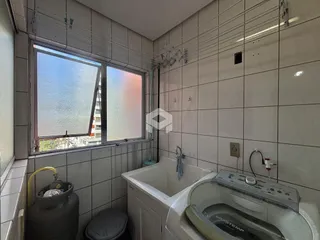 Banheiro com paredes de azulejo branco e janela.