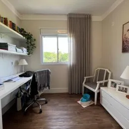 Foto de um ambiente interno com mesa de trabalho e cortinas em uma residência.