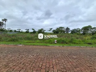 Vista externa da propriedade com gramado e área pavimentada sob céu nublado.