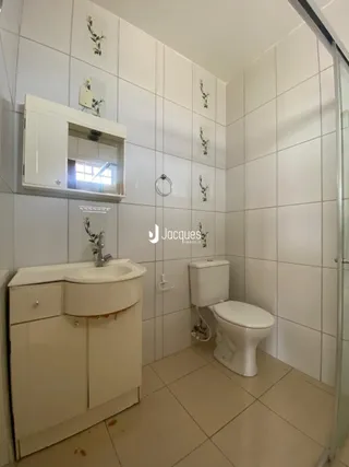 Foto de um banheiro com revestimento branco e piso claro.
