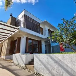 Fachada de uma residência com paredes brancas e detalhes em madeira.