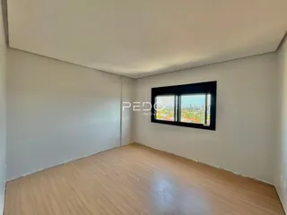 Ambiente interno de uma sala com piso de madeira e vista para a cidade.