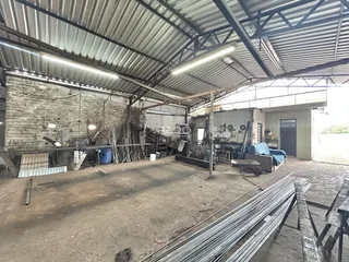 Vista interna de um espaço industrial em construção com piso de concreto e estrutura de telhado exposta.