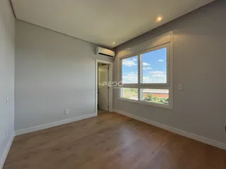 Ambiente interno de uma sala com piso de madeira clara e janela grande.