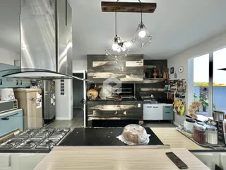 Foto de uma cozinha moderna com armários brancos e detalhes em pedra escura.