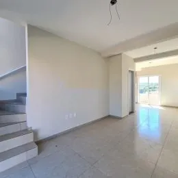 Vista interna de uma sala ampla com paredes brancas e piso claro.