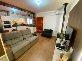 Sala de estar com sofá e piso de madeira em um imóvel em Lajeado.