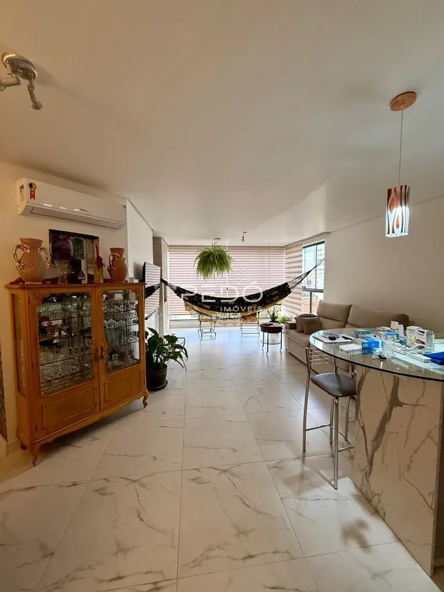 Sala de estar com piso de mármore claro e móvel de madeira.