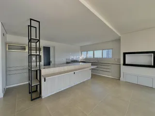Vista de uma cozinha moderna com ilha central e armários brancos.
