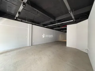 Interior de um espaço amplo com teto industrial e paredes brancas.