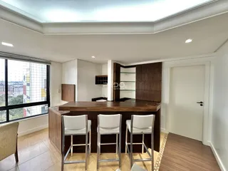 Sala de estar com bancada de madeira e grande janela em um imóvel no Brasil.
