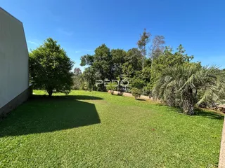 Vista externa de um jardim gramado com árvores ao fundo.