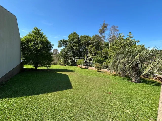 Vista externa de um jardim gramado com árvores ao fundo.