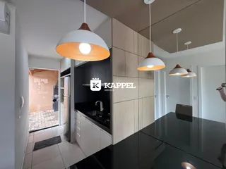 Cozinha moderna com armários escuros e iluminação pendente.