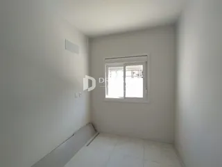 Vista interna de um cômodo com paredes brancas e piso de cerâmica.