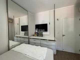 Quarto moderno com cabeceira e painel de TV em um apartamento.